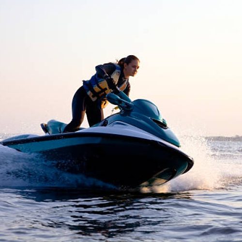 beautiful girl riding her jet skis in the sea at sunset. spray