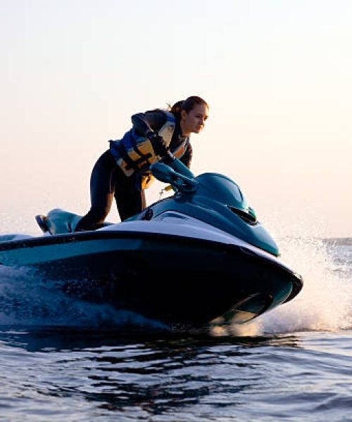 beautiful girl riding her jet skis in the sea at sunset. spray